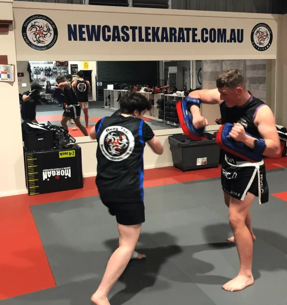 Adult students train striking techniques with pads at Newcastle Karate