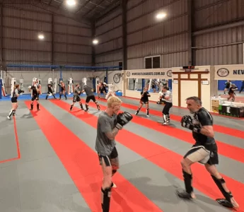 Kickboxing class in Newcastle dojo with adults practising sparring drills on mats