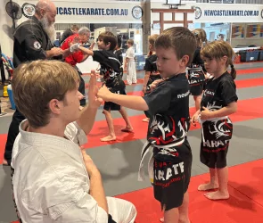 Kids karate class with instructors demonstrating hand positions
