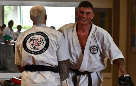 Adult karate students in black belts smiling together during dojo sparring session