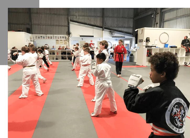 Young children practising punching drills on dojo mats during structured kids karate class